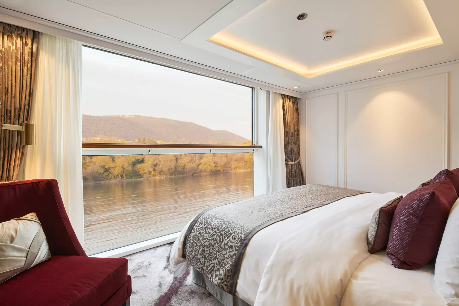 A Riverside suite with a king bed facing a full-height window onto the river